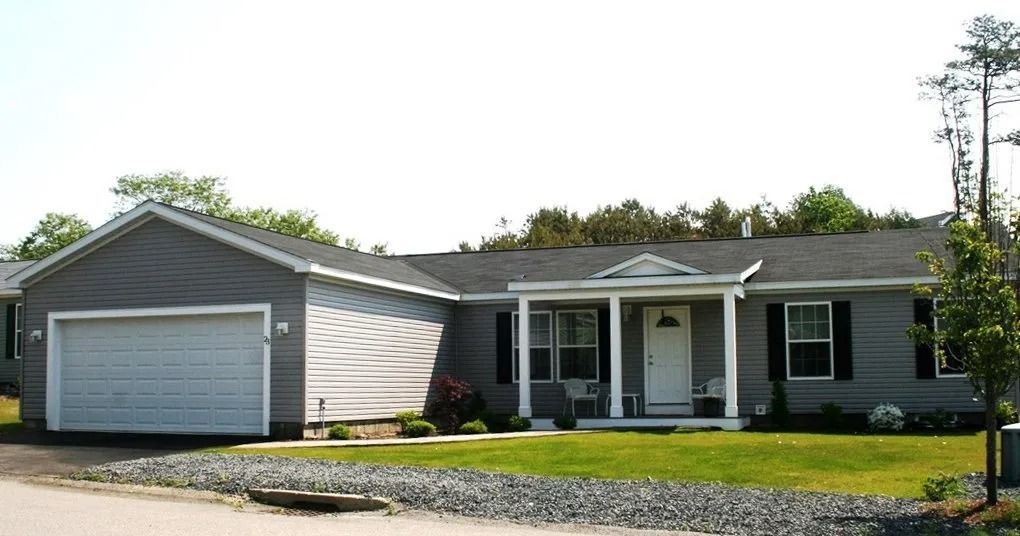Gray house with attached garage, small porch, and black shutters, set in a grassy yard.