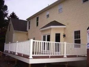 Back of a house with a multi-level deck featuring white railings and brown decking.