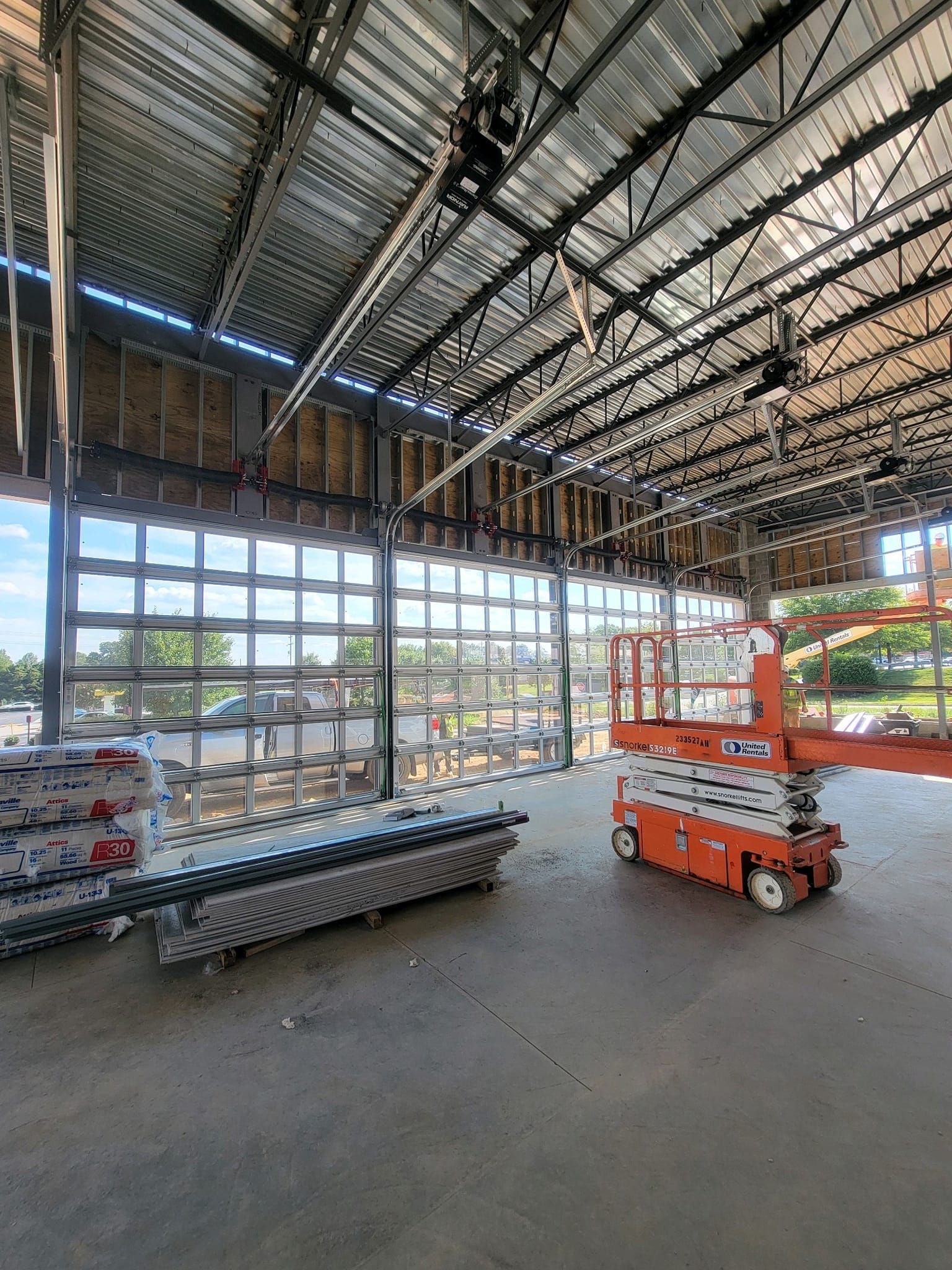 A large warehouse with a lot of windows and a scissor lift.