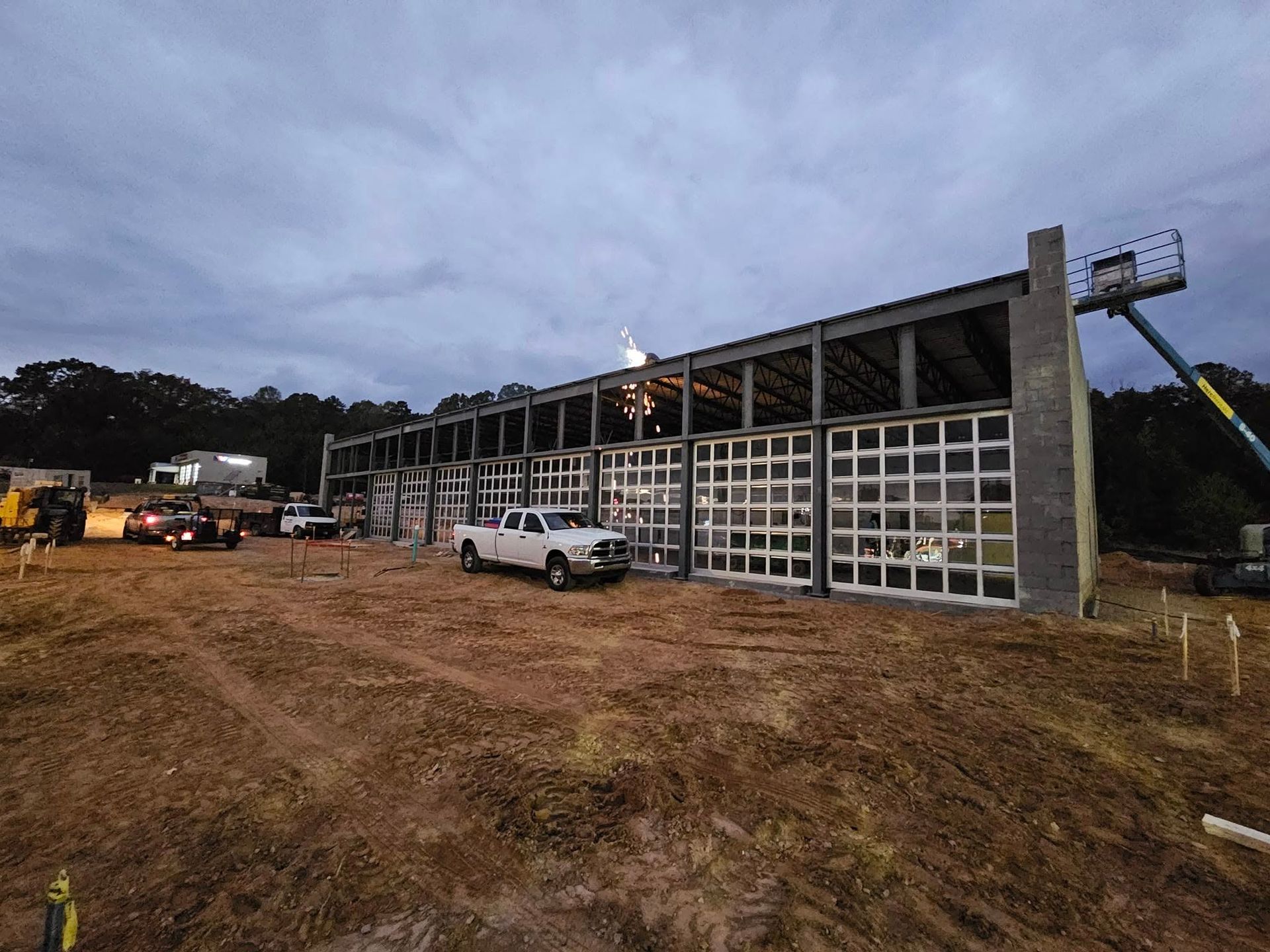 A white truck is parked in front of a large building under construction.