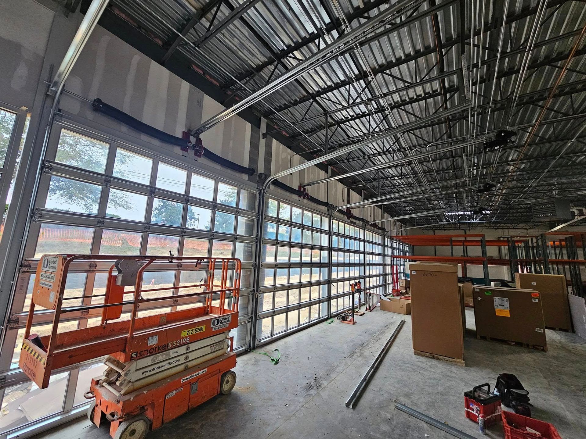 A large warehouse with a lot of windows and a scissor lift.