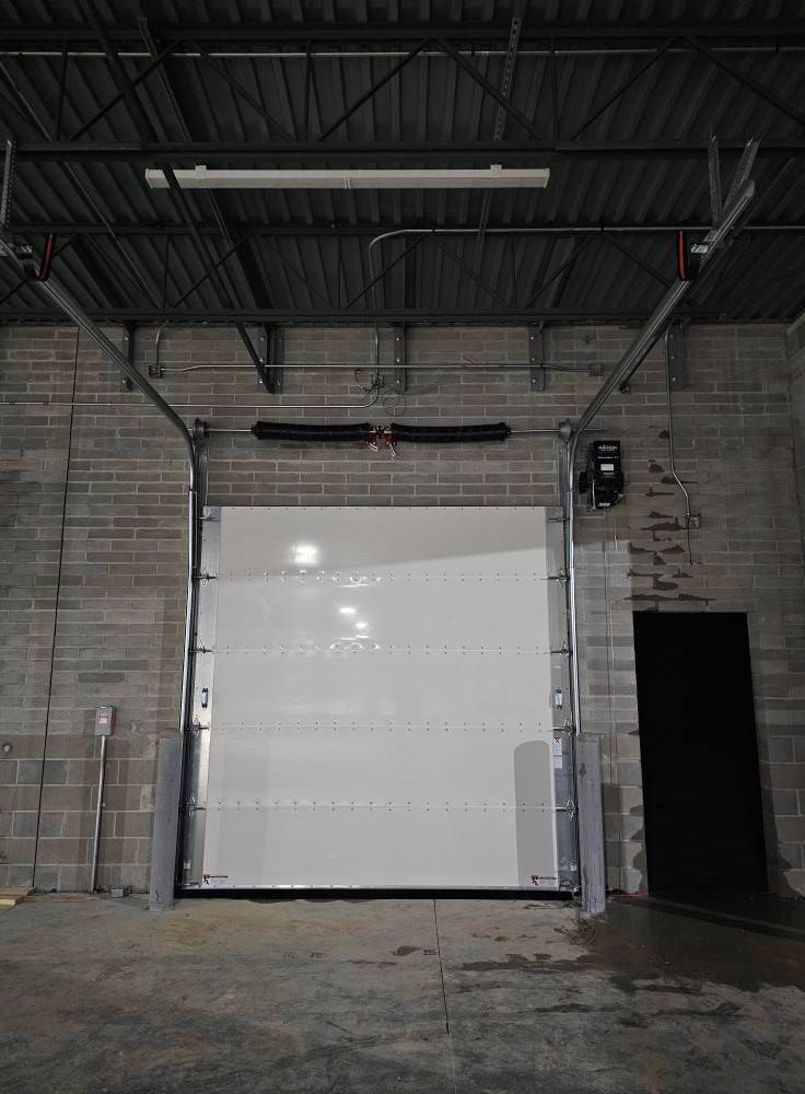 A white garage door is open in a warehouse.