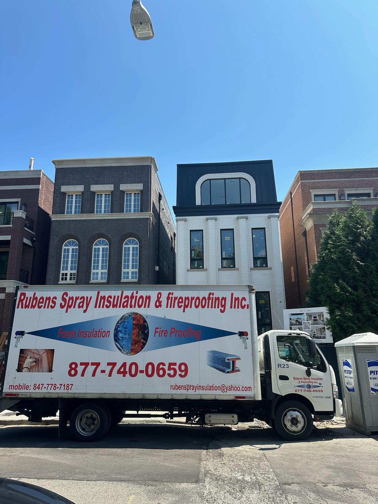 A roberts spray insulation truck is parked in front of a building