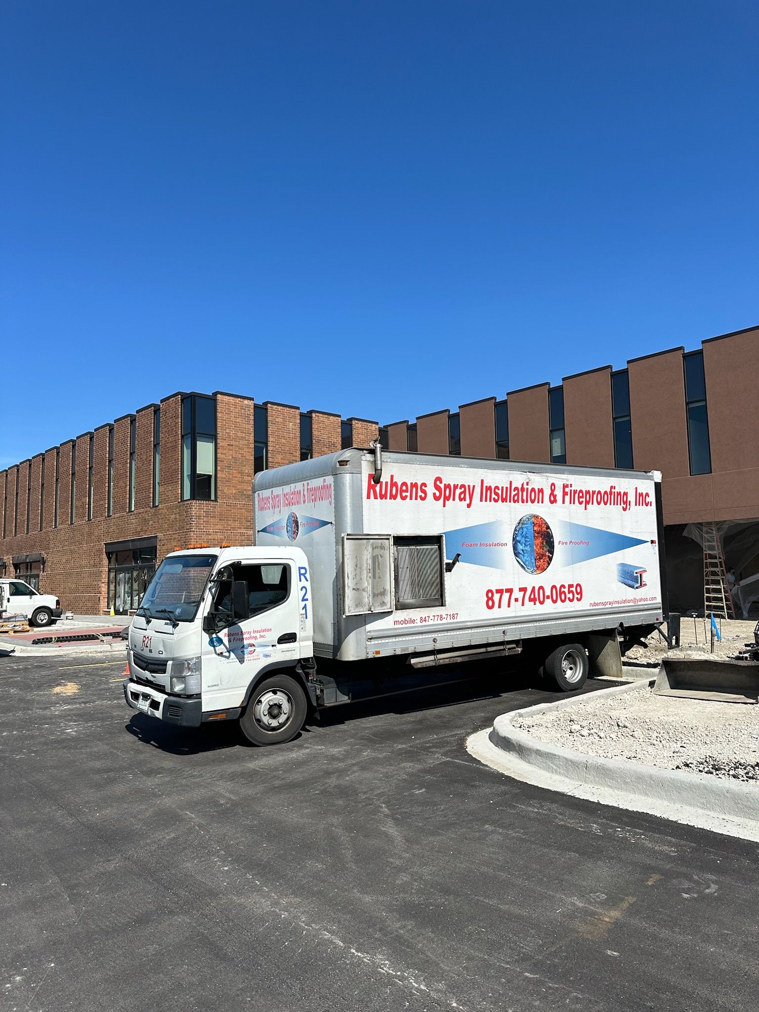 A white truck is parked in front of a large brick building.