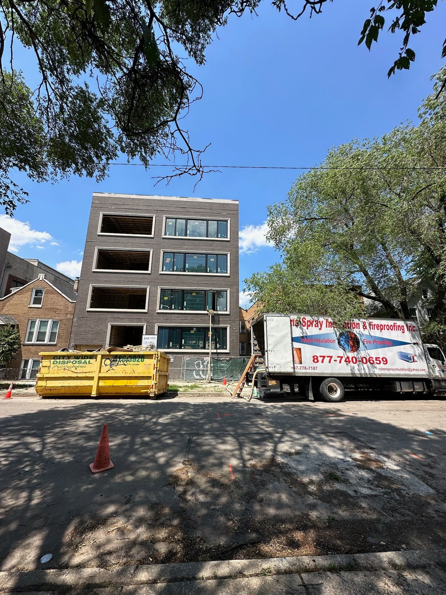 A white truck is parked in front of a building under construction.