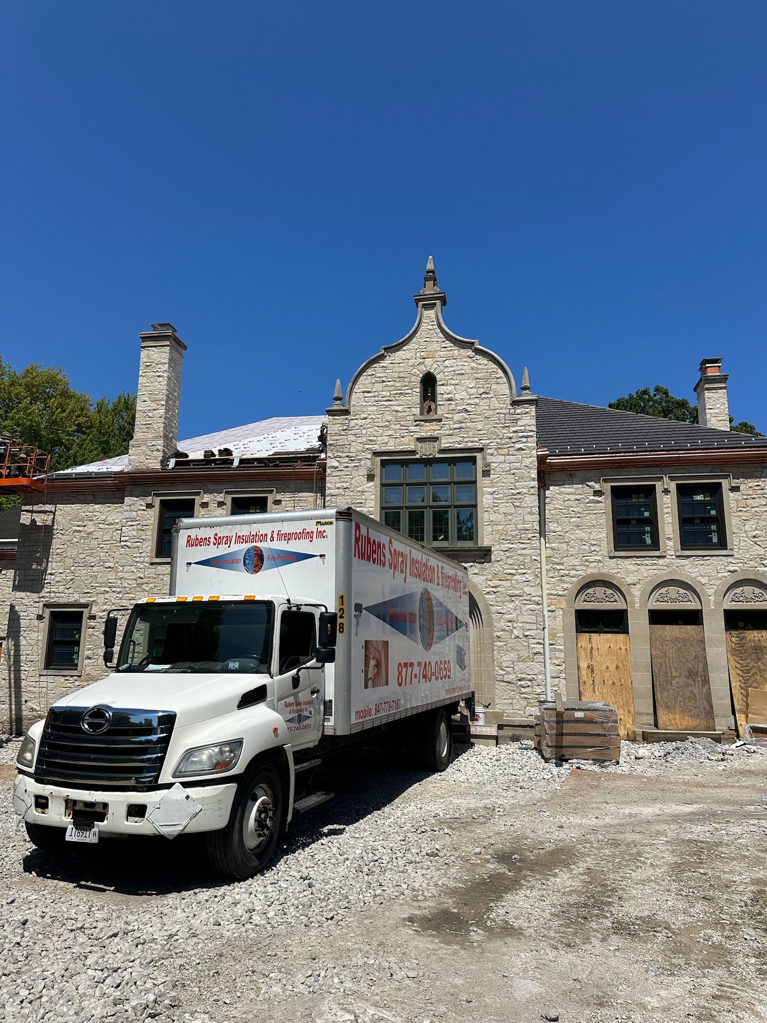 A white truck is parked in front of a large stone building.