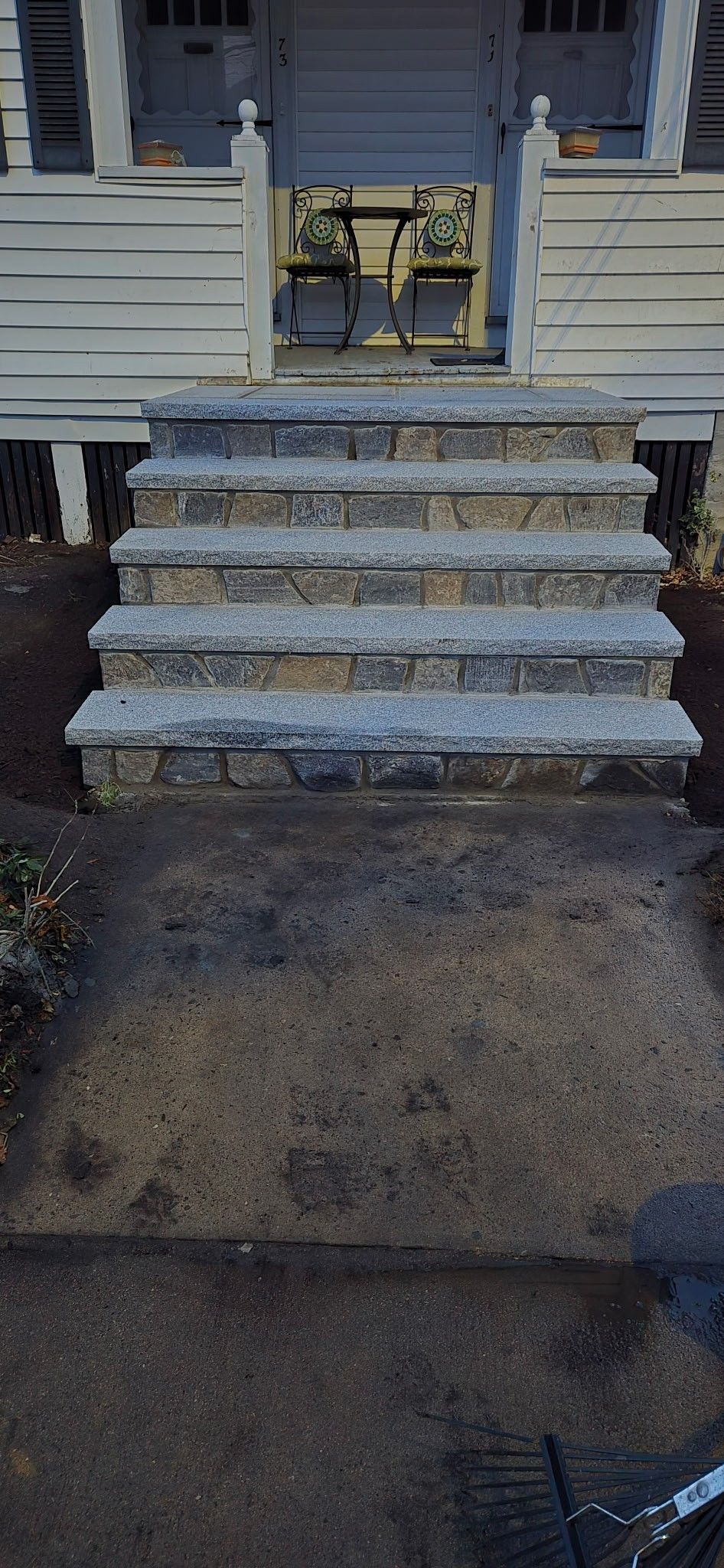 Concrete steps leading to the entrance of a weathered, light-colored house.