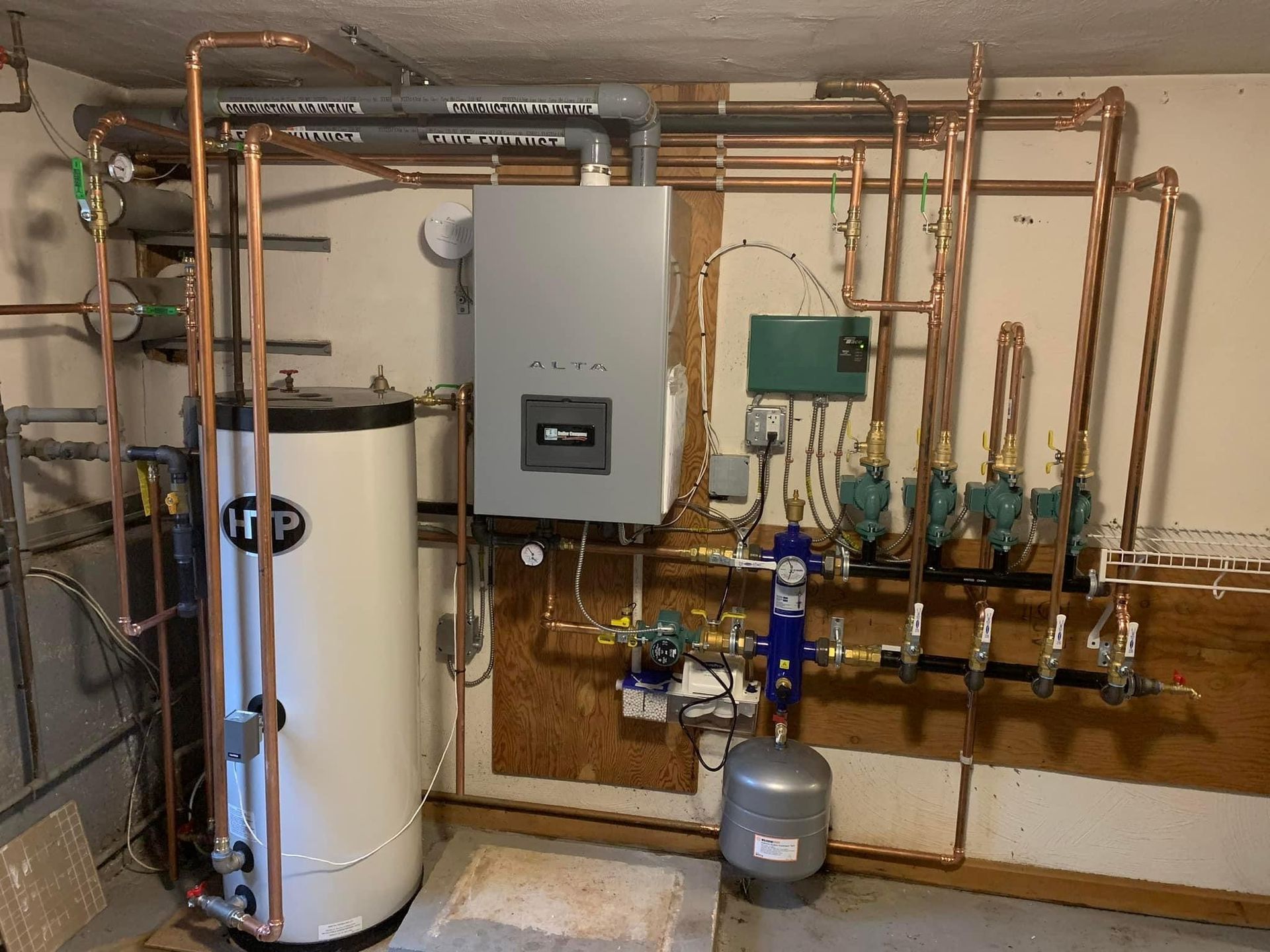 A room with a water heater and copper pipes.