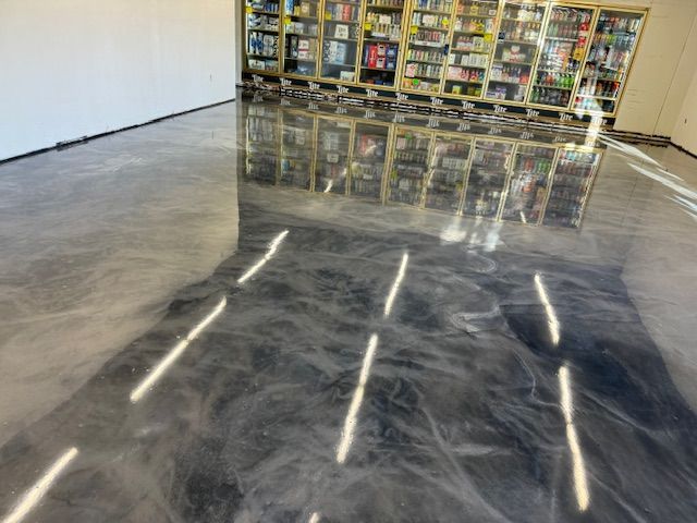 Shiny, metallic-look flooring reflecting shelves of books. Sunlight creates bright streaks on the dark, swirled surface.