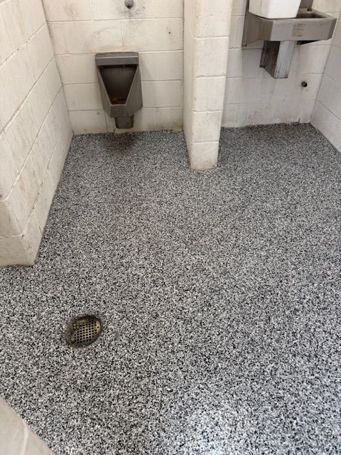 Public restroom with gray speckled floor, urinal, and sink.