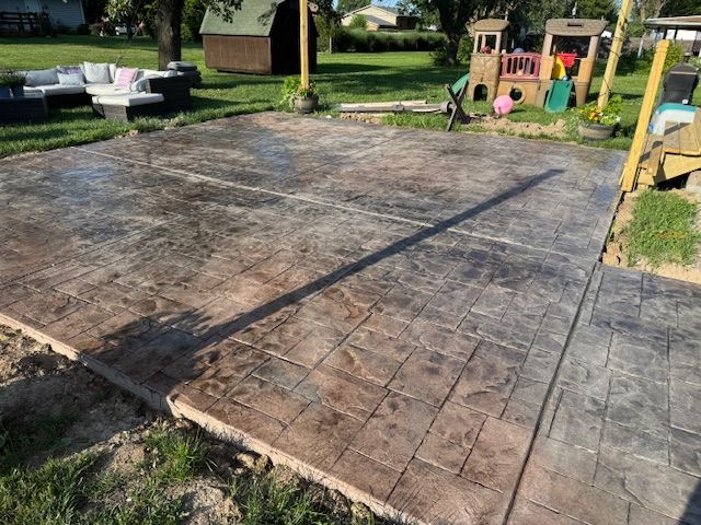Stamped concrete patio with a playhouse and outdoor seating in a backyard.