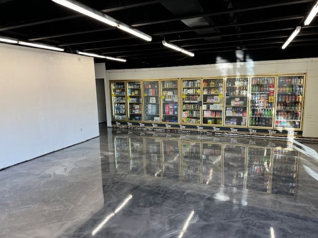 Empty store interior with a wall and refrigerated display cases full of products; reflective floor.