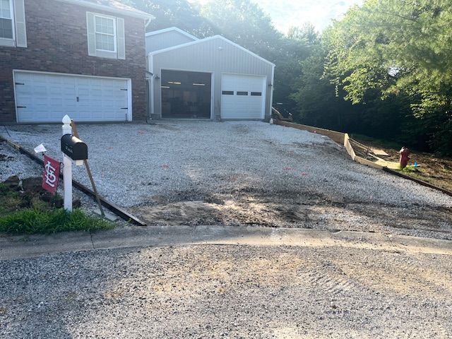 Gravel driveway leads to a brick house and detached garage. A mailbox is in the foreground.
