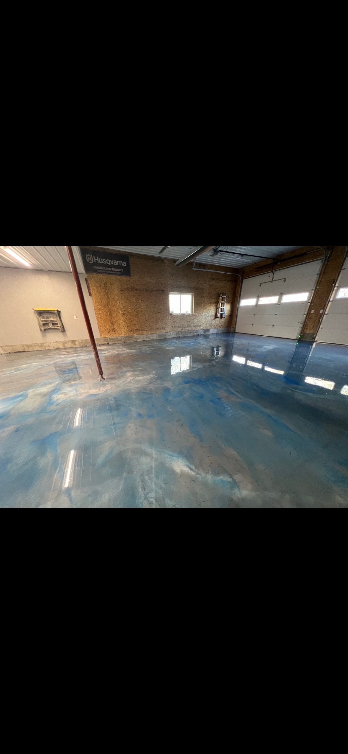 Interior view of a warehouse with a blue and silver epoxy floor.
