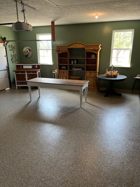 A garage converted into a living space, featuring furniture like a large table and a hutch, painted green.