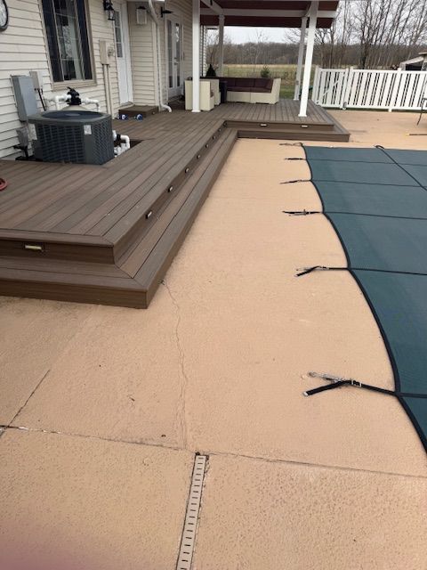 A deck with brown stairs leads to a pool covered with a blue tarp.