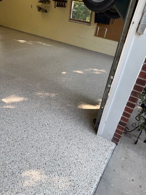 Garage with epoxy-coated floor, light gray with speckles, open doorway, bright interior, brick column.