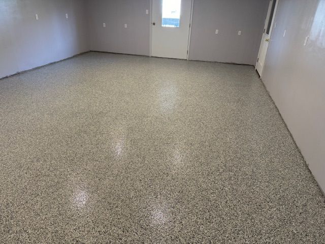 Gray epoxy floor in a room with light gray walls and a white door.