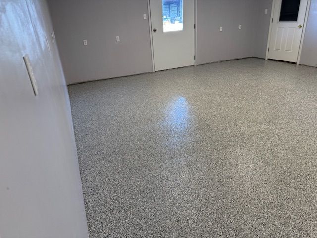 Room with gray speckled epoxy floor and gray walls. Two white doors are visible.