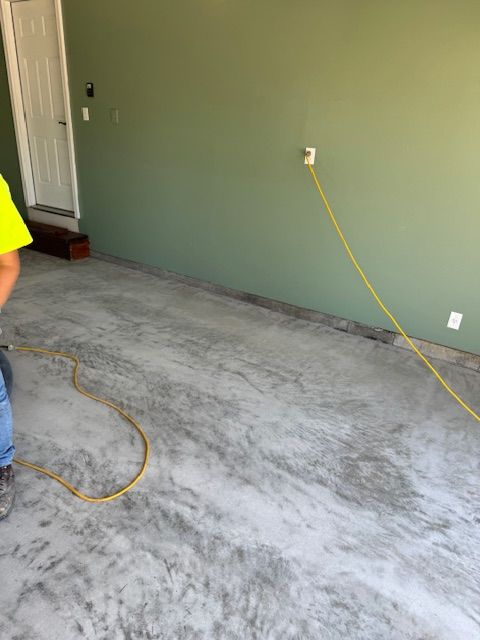 Garage interior, concrete floor, green walls. Yellow extension cord plugged into an outlet.