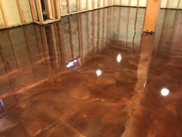 Brown metallic epoxy flooring in a room with exposed wooden studs. Reflective surface.