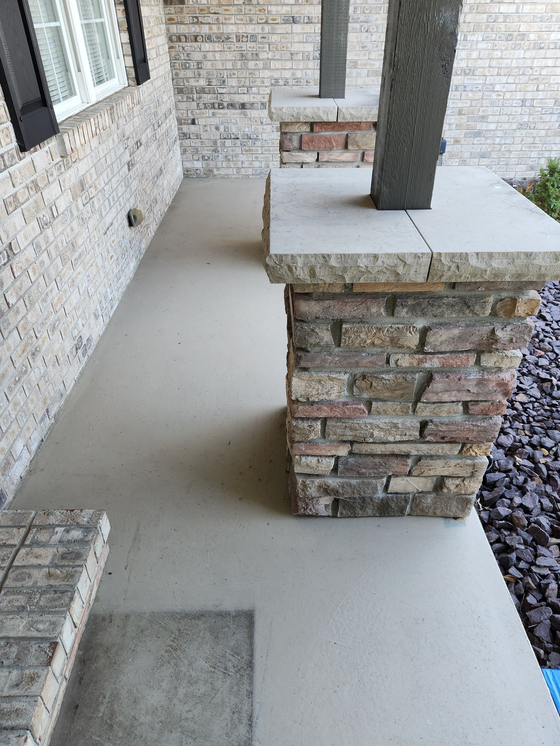 Covered porch with stone columns and a concrete floor.