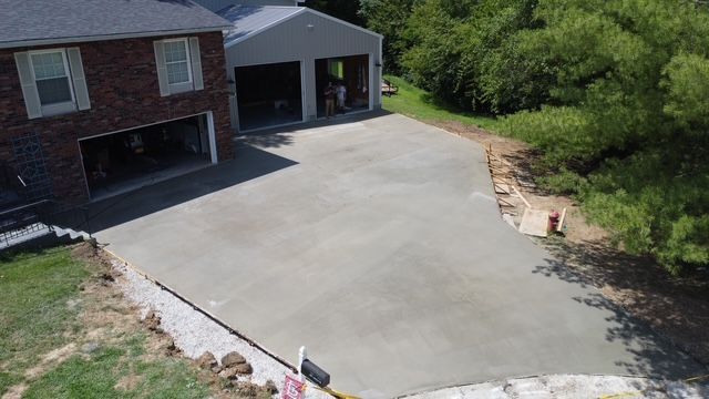 Newly poured concrete driveway leading to a house and garage; gray.