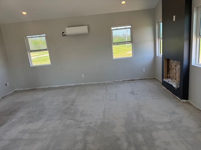 Empty room with gray walls, windows, and a black fireplace.