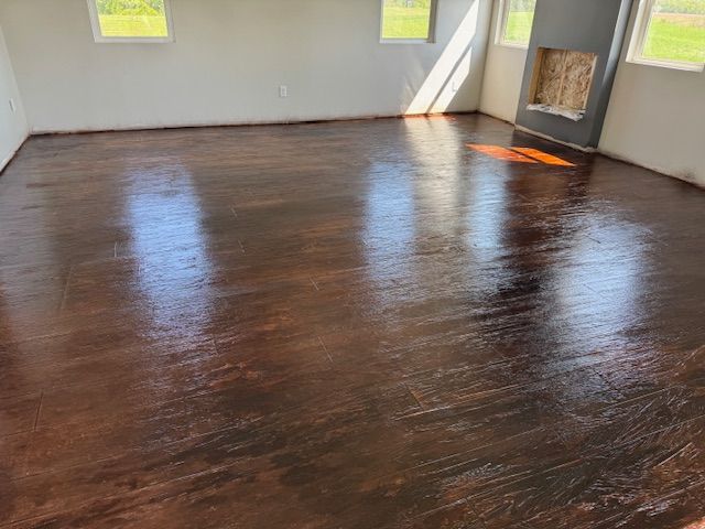 Brown and bronze stained concrete floor with a glossy finish in an empty room, windows visible.