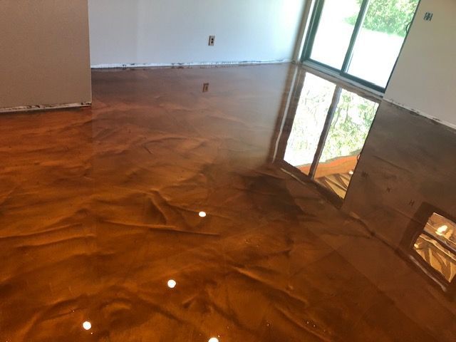 Metallic bronze epoxy floor reflects light in a room with a large window.