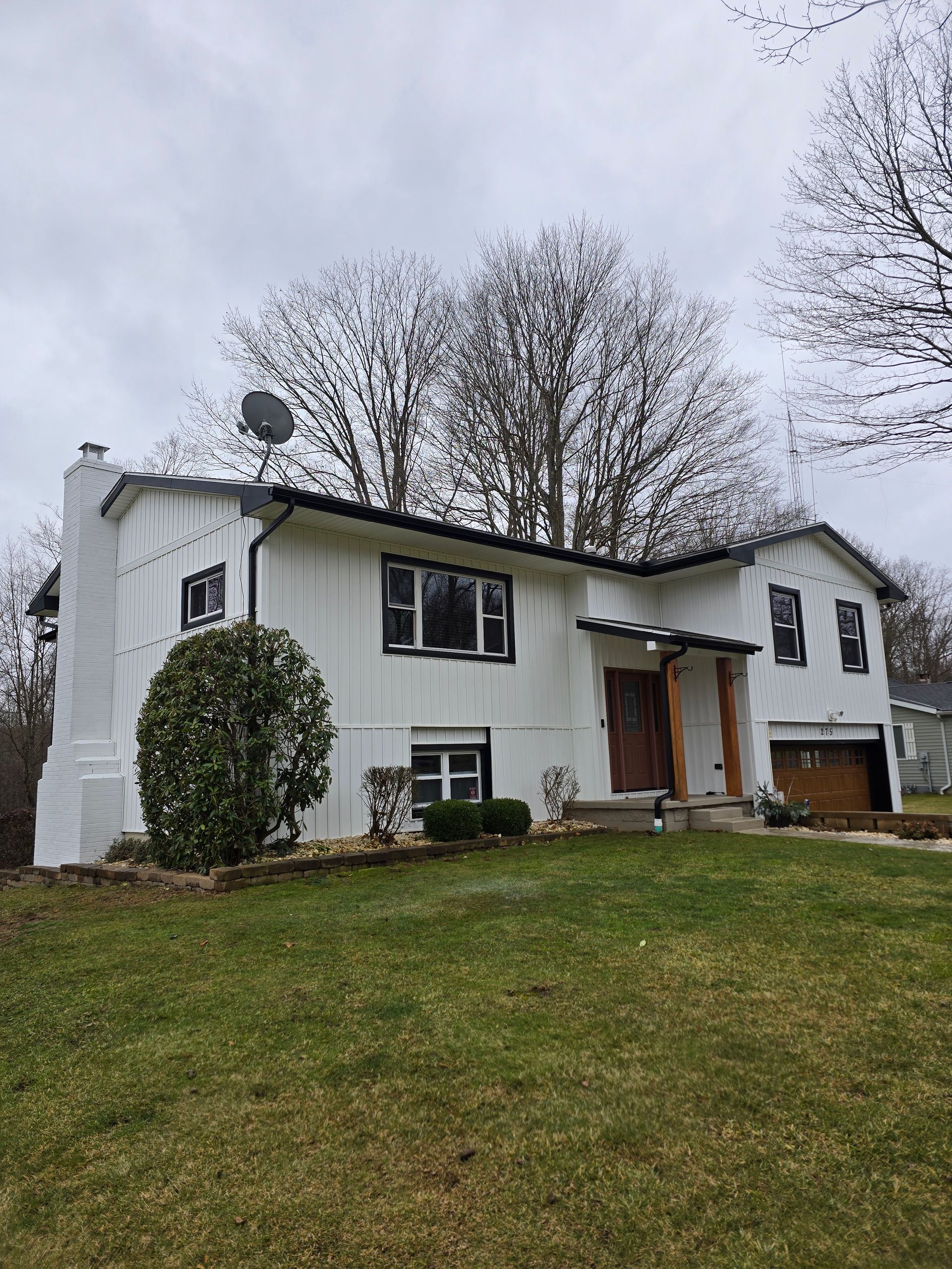 A white house with black shutters and a satellite dish on the roof.