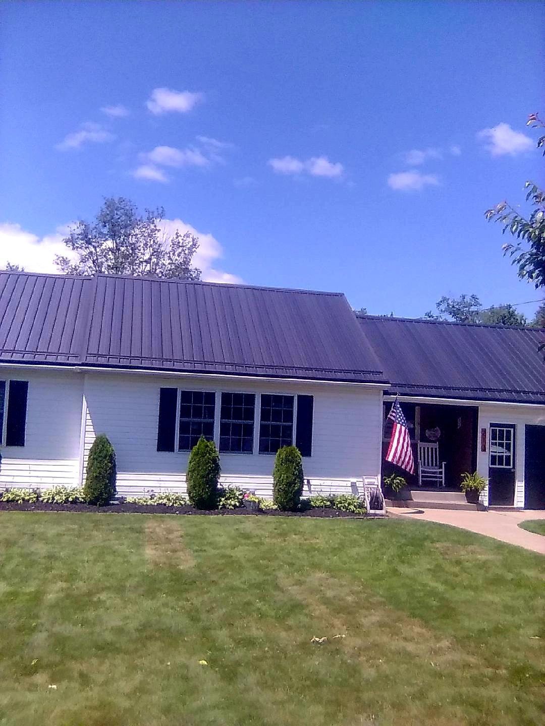 A white house with a black roof and a large lawn in front of it