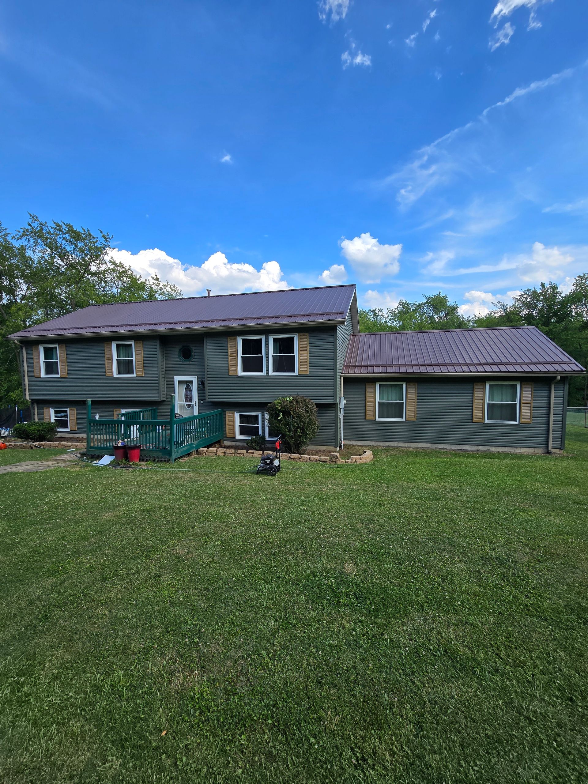 A large house with a metal roof is sitting on top of a lush green field.