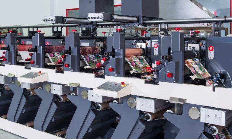 Row of industrial machines with white and gray parts in a factory setting.