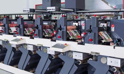 Automated industrial machine line with gray and white components in a factory setting.