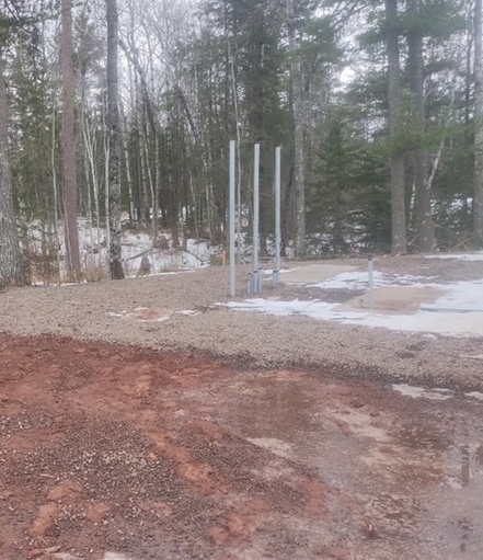 A dirt road in the middle of a forest with trees in the background.
