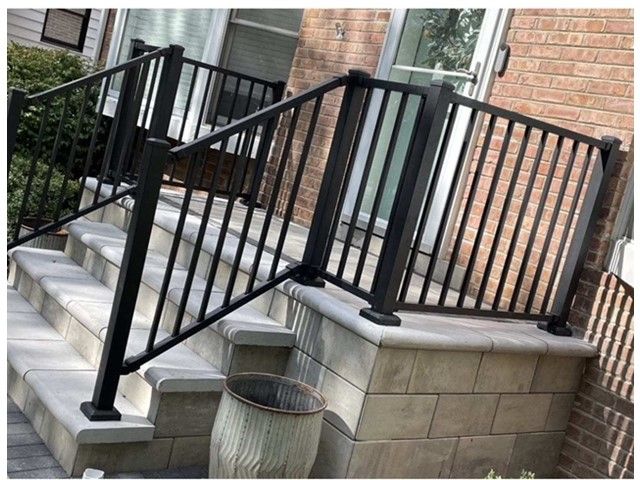 A black railing on a set of stairs next to a brick building.