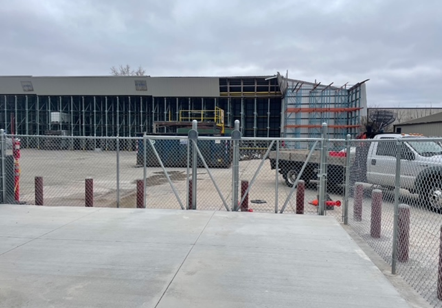 A chain link fence surrounds a concrete area in front of a building.