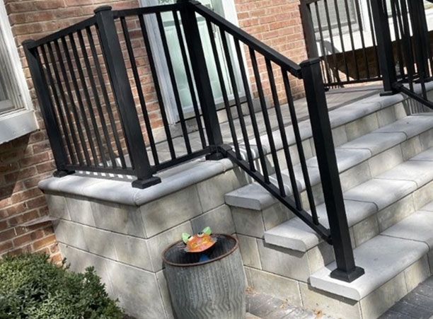 A black railing on a set of stairs next to a brick wall