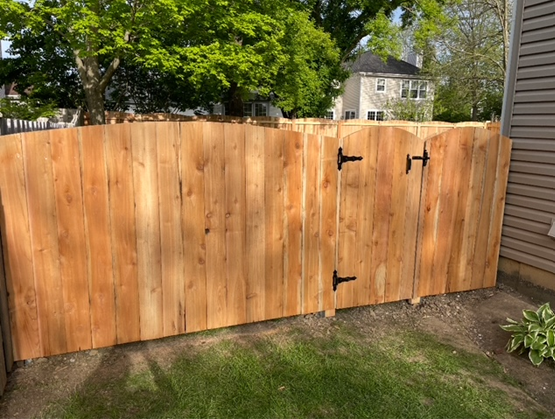A wooden fence with a gate in the backyard of a house.