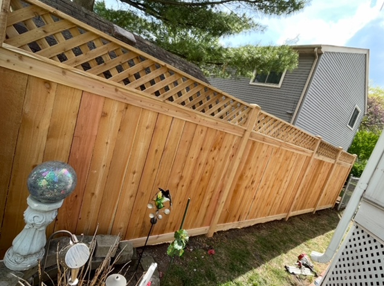 A wooden fence with a lattice top is in front of a house.