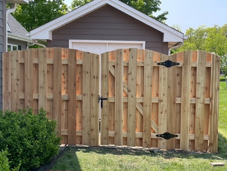 A wooden fence with a gate is in front of a house.