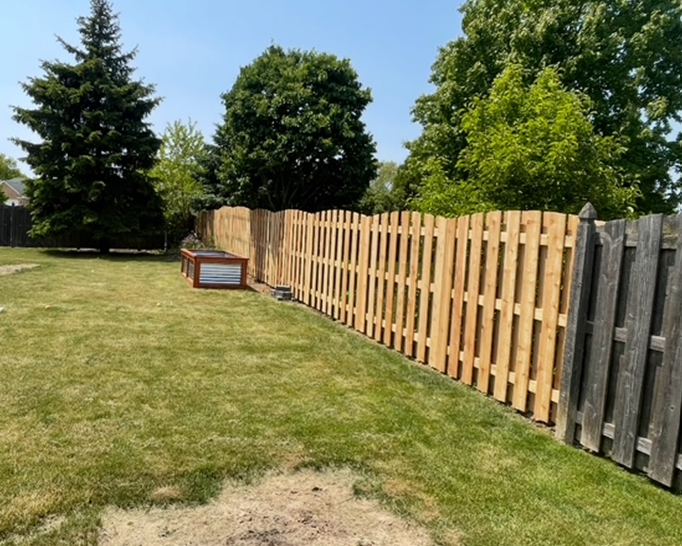 A wooden fence surrounds a lush green yard