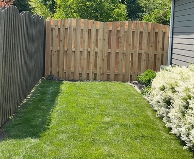A wooden fence in a green yard.