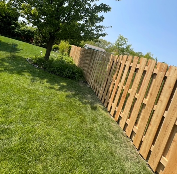 A wooden fence surrounds a lush green yard