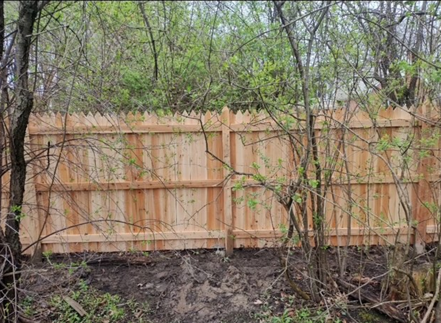 A wooden fence is surrounded by trees in a forest.