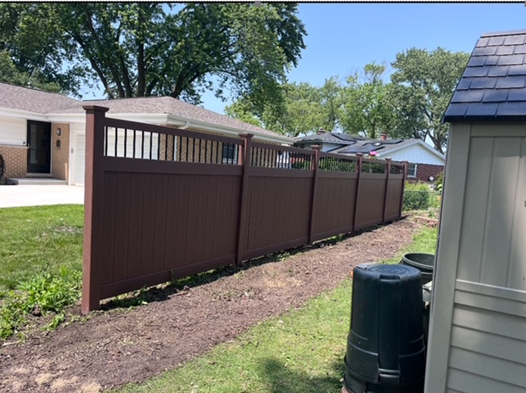 Brown privacy fence in a yard, separating two houses. A compost bin sits in the foreground.