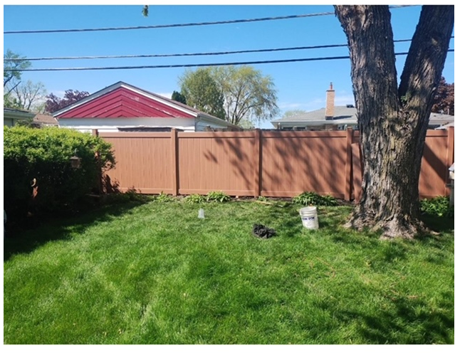 A backyard with a wooden fence and a tree