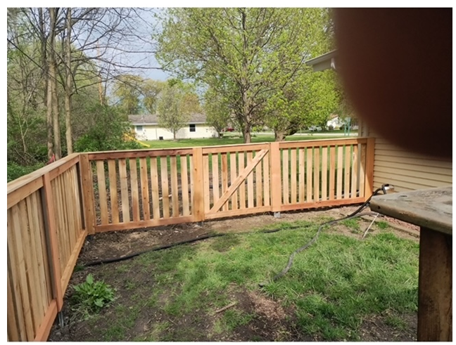 A wooden fence is surrounding a lush green yard.