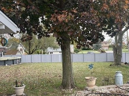 A backyard with a white fence and a tree in the middle of it.